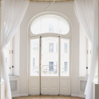 Romantic French Doors, framed by soft white sheer curtains that drape to the floor